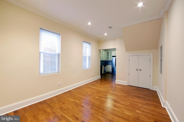 unfurnished room with visible vents, crown molding, baseboards, electric panel, and light wood-style flooring