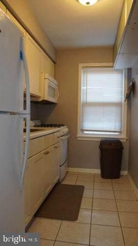 kitchen with white appliances, white cabinetry, and light tile patterned floors