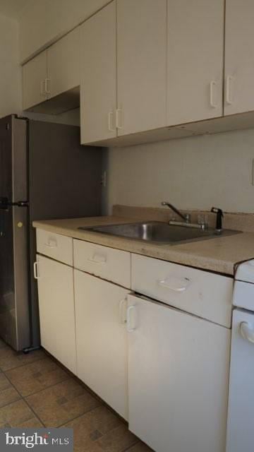 kitchen featuring white cabinetry, sink, and stainless steel fridge