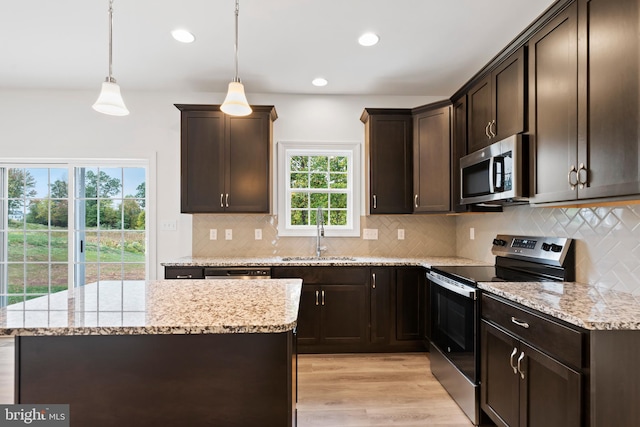 kitchen featuring sink, dark brown cabinets, light hardwood / wood-style flooring, appliances with stainless steel finishes, and pendant lighting