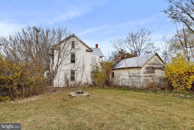 back of house with an outbuilding and a yard