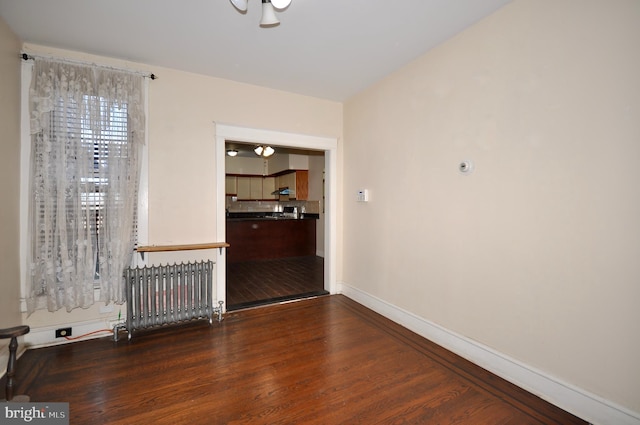 spare room featuring radiator and dark wood-type flooring