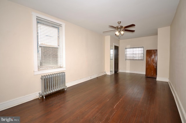 empty room with ceiling fan, radiator, and dark hardwood / wood-style flooring