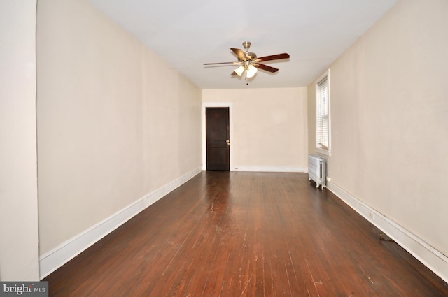 spare room with dark wood-type flooring, radiator heating unit, and ceiling fan