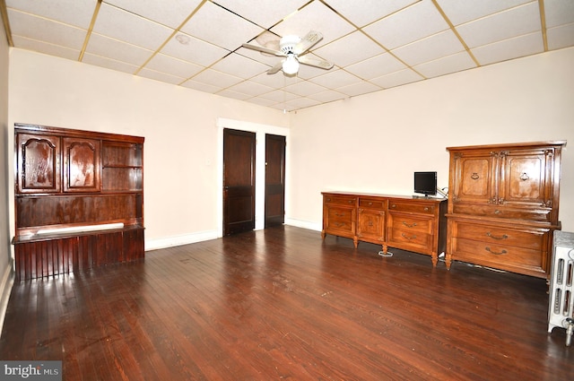 interior space with ceiling fan, dark hardwood / wood-style flooring, and a drop ceiling