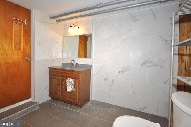 bathroom with tile patterned flooring, vanity, tile walls, and toilet