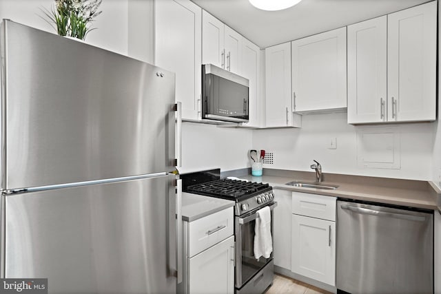 kitchen with white cabinetry, stainless steel appliances, and sink