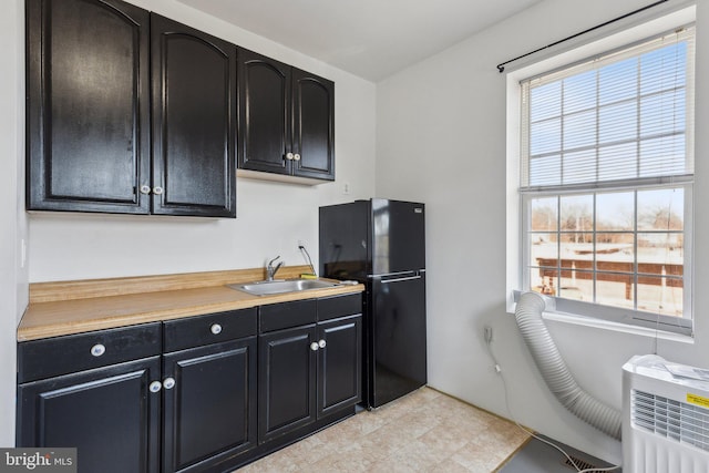 kitchen featuring black refrigerator, sink, and radiator