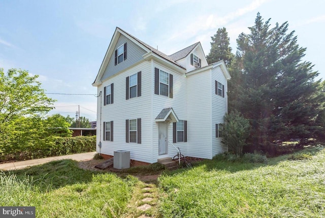 view of property with cooling unit and a front lawn