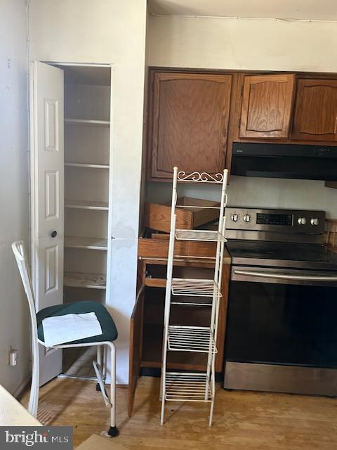 kitchen with stainless steel electric range oven and light hardwood / wood-style flooring