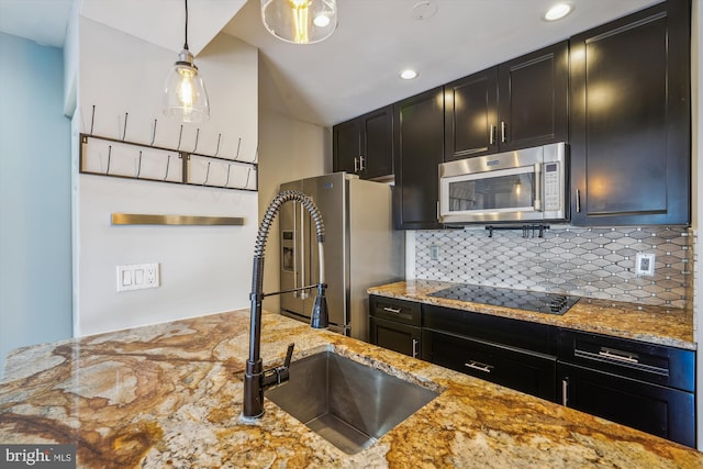 kitchen with pendant lighting, sink, backsplash, stainless steel appliances, and light stone countertops