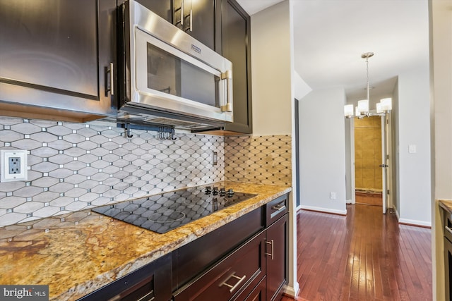 kitchen with light stone countertops, pendant lighting, black electric stovetop, and decorative backsplash