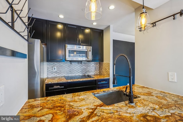 kitchen featuring sink, light stone counters, hanging light fixtures, stainless steel appliances, and backsplash