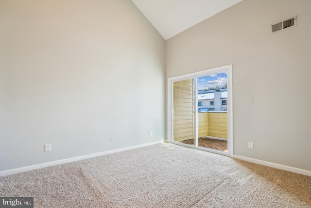 carpeted spare room featuring high vaulted ceiling