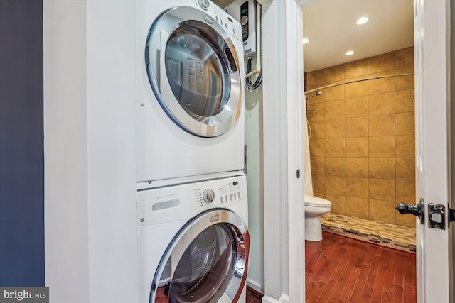 laundry room with stacked washer and clothes dryer and dark hardwood / wood-style floors