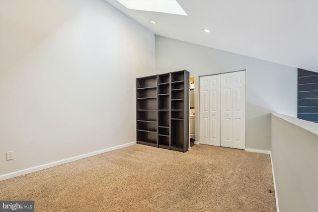 unfurnished bedroom featuring a closet, carpet flooring, high vaulted ceiling, and a skylight