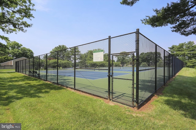 view of tennis court featuring a lawn