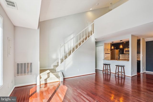 interior space with dark wood-type flooring and a towering ceiling