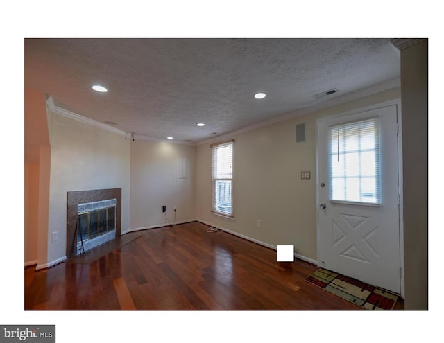 interior space featuring dark hardwood / wood-style flooring, ornamental molding, and a textured ceiling