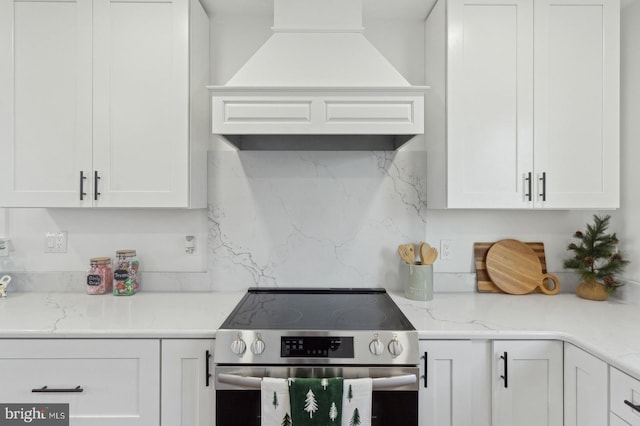 kitchen with stainless steel range with electric stovetop, custom exhaust hood, and white cabinets