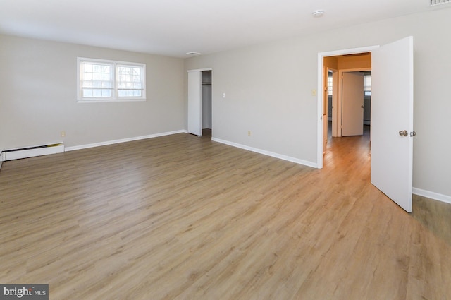 unfurnished room with baseboard heating and light hardwood / wood-style floors