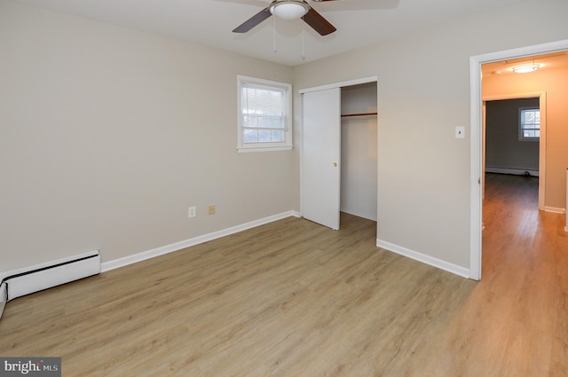 unfurnished bedroom with ceiling fan, light hardwood / wood-style floors, a closet, and a baseboard heating unit