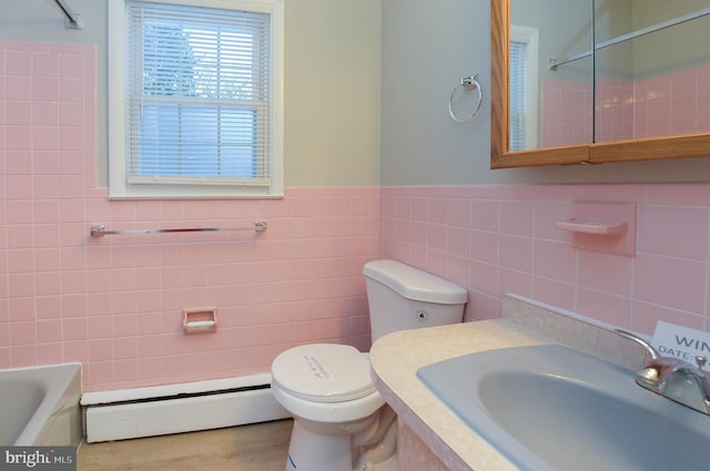 bathroom with a bathing tub, sink, tile walls, a baseboard heating unit, and toilet