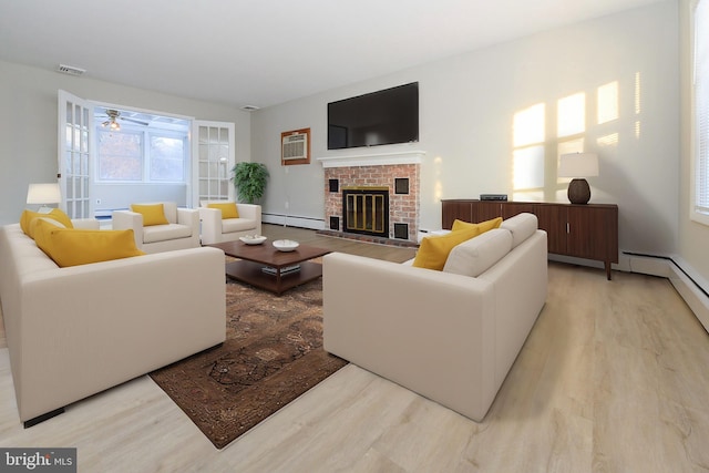 living room featuring a baseboard heating unit, light hardwood / wood-style flooring, and a brick fireplace