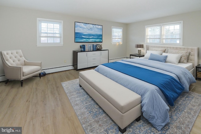 bedroom with multiple windows, baseboard heating, and light hardwood / wood-style flooring