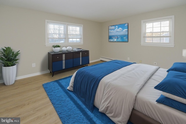 bedroom with wood-type flooring and a baseboard heating unit