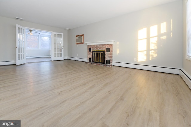 unfurnished living room with a baseboard heating unit, a fireplace, light hardwood / wood-style floors, and a wall mounted AC