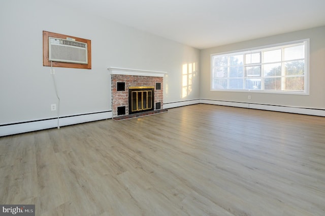 unfurnished living room featuring a brick fireplace, a wall unit AC, baseboard heating, and light wood-type flooring