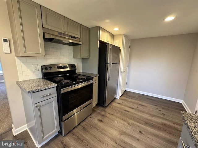 kitchen featuring gray cabinets, appliances with stainless steel finishes, light stone counters, wood-type flooring, and decorative backsplash