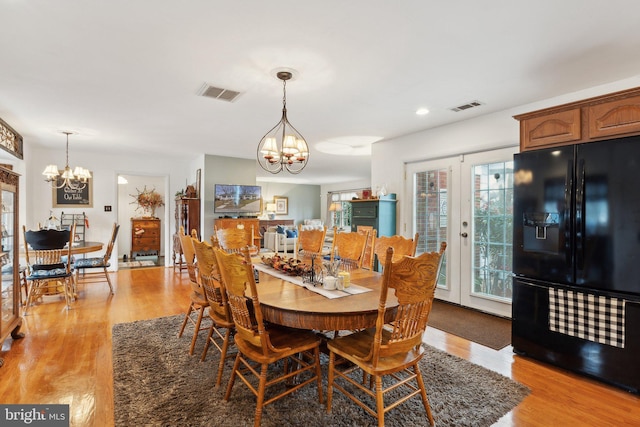 dining area featuring an inviting chandelier, light hardwood / wood-style floors, and french doors