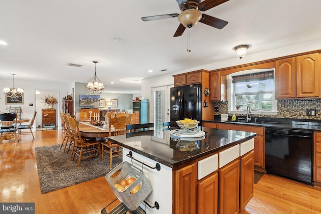 kitchen featuring sink, light hardwood / wood-style flooring, black appliances, a kitchen island, and decorative light fixtures