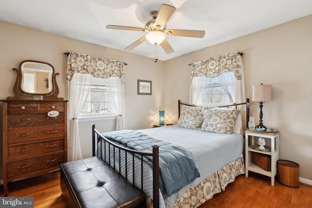 bedroom with ceiling fan, dark hardwood / wood-style flooring, and multiple windows