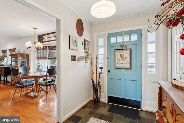 entryway featuring an inviting chandelier, ornamental molding, and dark hardwood / wood-style floors