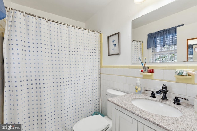 bathroom with tile walls, vanity, toilet, and a shower with shower curtain