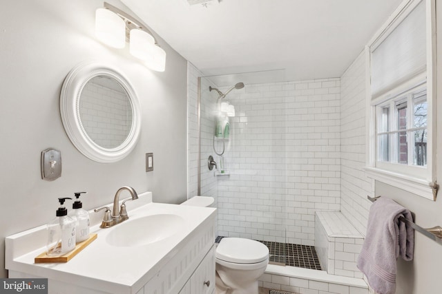 bathroom with tiled shower, vanity, and toilet