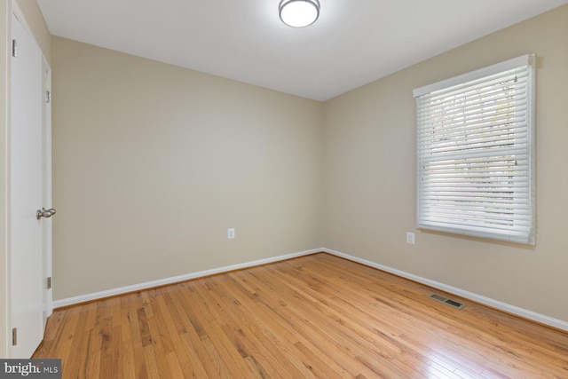 spare room featuring baseboards, visible vents, and light wood finished floors