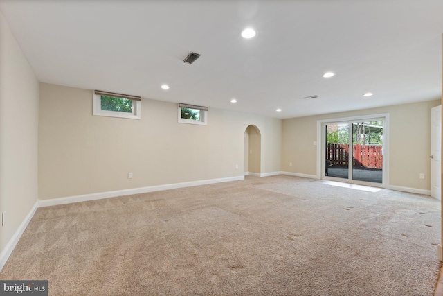 spare room with light colored carpet, baseboards, arched walkways, and recessed lighting