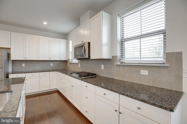 kitchen with dark stone countertops, tasteful backsplash, stainless steel appliances, and white cabinets