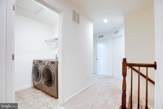 clothes washing area featuring light colored carpet and washer and dryer