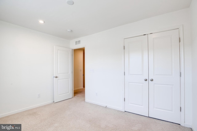 unfurnished bedroom featuring light colored carpet and a closet