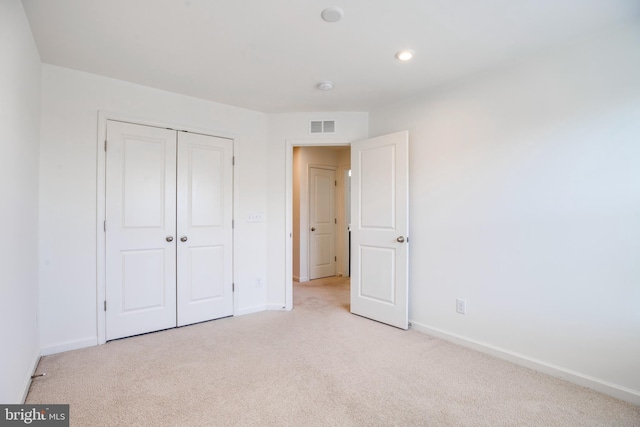 unfurnished bedroom featuring light carpet and a closet