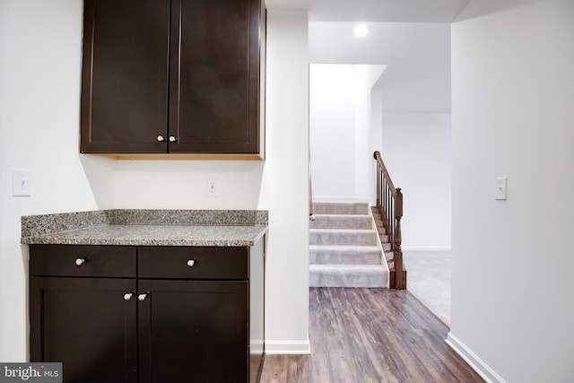 kitchen featuring dark brown cabinets, light stone counters, and dark hardwood / wood-style floors