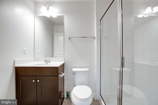 bathroom with vanity, a shower with door, and toilet