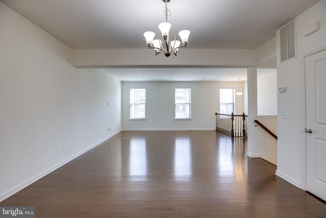 spare room featuring an inviting chandelier and dark hardwood / wood-style flooring