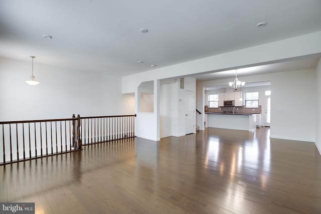 unfurnished room with dark wood-type flooring and a chandelier