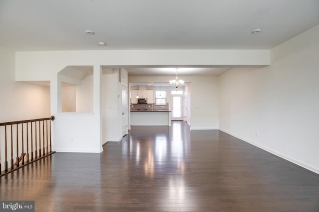 unfurnished living room with dark hardwood / wood-style floors and a notable chandelier